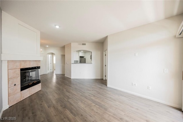 7400 W Flamingo Rd Unit 1082, Las Vegas, NV 89147 - unfurnished living room featuring arched walkways, wood finished floors, a tiled fireplace, and recessed lighting