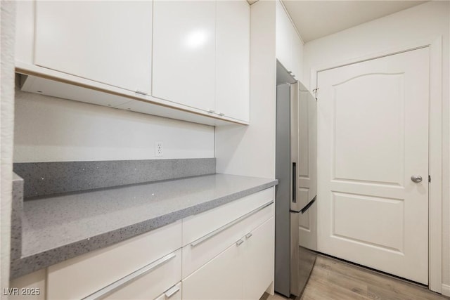 7400 W Flamingo Rd Unit 1082, Las Vegas, NV 89147 - kitchen with stainless steel refrigerator with ice dispenser, white cabinets, light wood-style floors, and light stone countertops