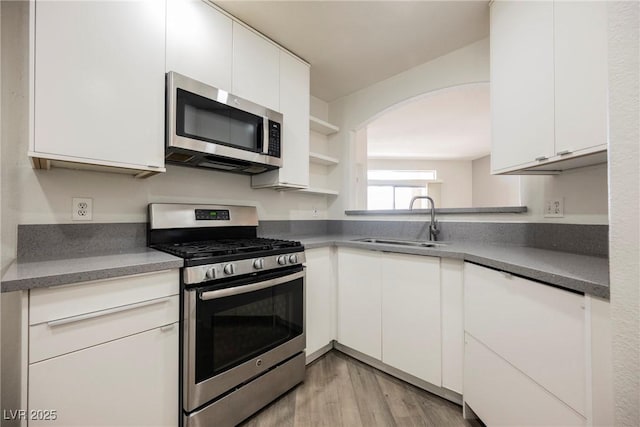 7400 W Flamingo Rd Unit 1082, Las Vegas, NV 89147 - kitchen featuring stainless steel appliances, open shelves, white cabinetry, and arched walkways