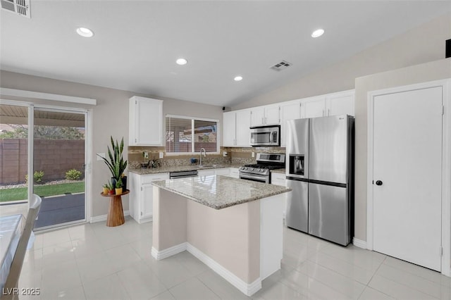 509 Regal Robin Way N, Las Vegas, NV 89084 - kitchen with appliances with stainless steel finishes, a center island, light stone countertops, white cabinetry, and tasteful backsplash