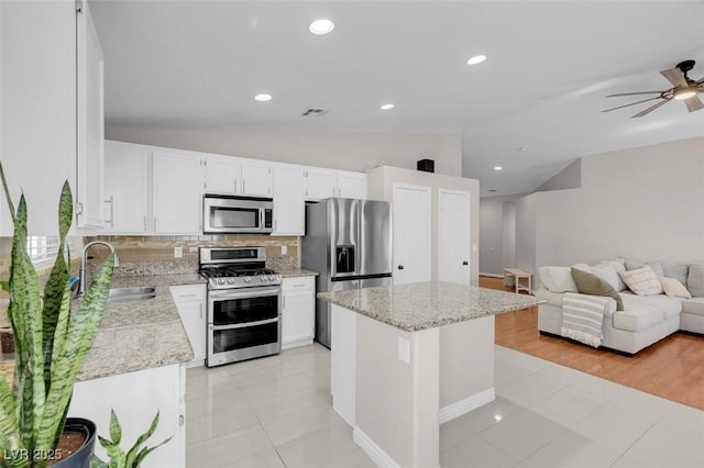 509 Regal Robin Way N, Las Vegas, NV 89084 - kitchen with appliances with stainless steel finishes, a kitchen island, light tile patterned floors, decorative backsplash, and a sink