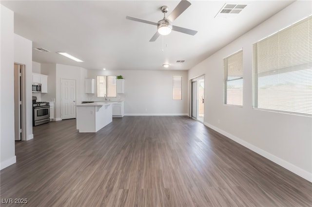6140 Passionate Ct, North Las Vegas, NV 89031 - unfurnished living room featuring a ceiling fan, baseboards, dark wood-style floors, and healthy amount of natural light