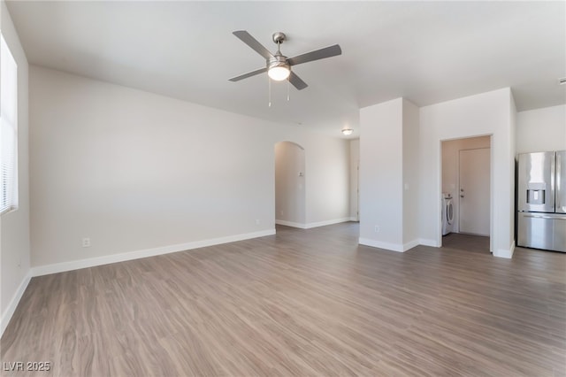 6140 Passionate Ct, North Las Vegas, NV 89031 - unfurnished living room with washing machine and clothes dryer, ceiling fan, arched walkways, wood finished floors, and baseboards