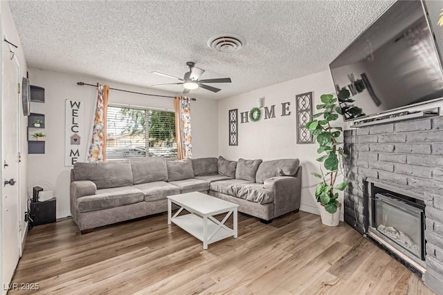 3417 Lillis Cir, North Las Vegas, NV 89030 - living area featuring ceiling fan, light wood-style floors, a brick fireplace, and a textured ceiling