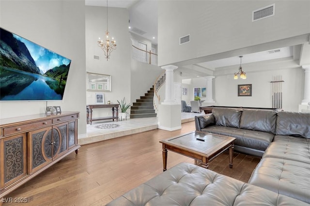 4326 Spooner Lake Cir, Las Vegas, NV 89147 - living room featuring decorative columns, wood finished floors, a chandelier, a high ceiling, and stairs