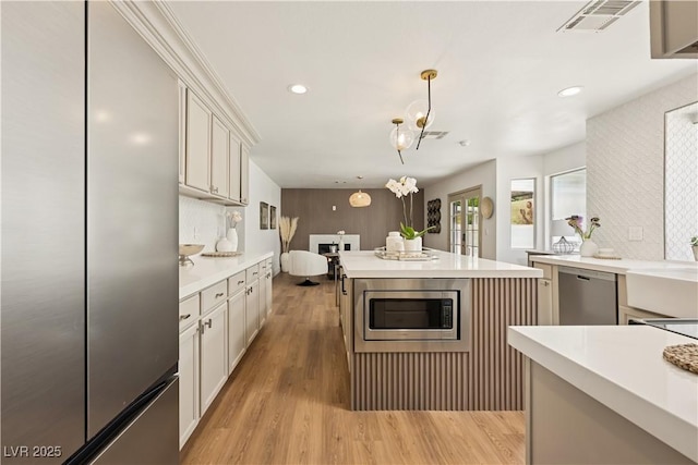 7825 Desert Bell Ave, Las Vegas, NV 89128 - kitchen with stainless steel appliances, light countertops, decorative light fixtures, light wood-style flooring, and a kitchen island