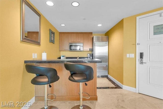 2000 N Fashion Show Dr Unit 5326, Las Vegas, NV 89109 - kitchen featuring stainless steel appliances, baseboards, dark countertops, a kitchen bar, and recessed lighting