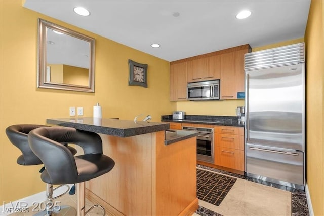 2000 N Fashion Show Dr Unit 5326, Las Vegas, NV 89109 - kitchen with appliances with stainless steel finishes, a peninsula, dark countertops, a kitchen bar, and recessed lighting