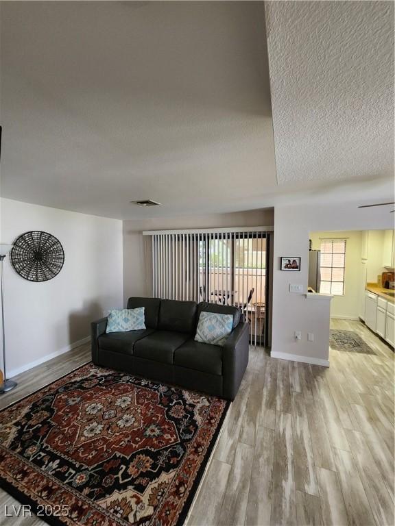4805 S Torrey Pines Dr Unit 101, Las Vegas, NV 89103 - living room with light wood-style flooring, a textured ceiling, and baseboards
