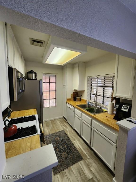 4805 S Torrey Pines Dr Unit 101, Las Vegas, NV 89103 - kitchen with stainless steel microwave, a sink, white dishwasher, white cabinetry, and a textured ceiling