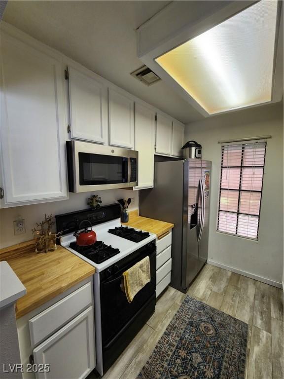 4805 S Torrey Pines Dr Unit 101, Las Vegas, NV 89103 - kitchen featuring stainless steel appliances, white cabinetry, light wood-type flooring, and wood counters