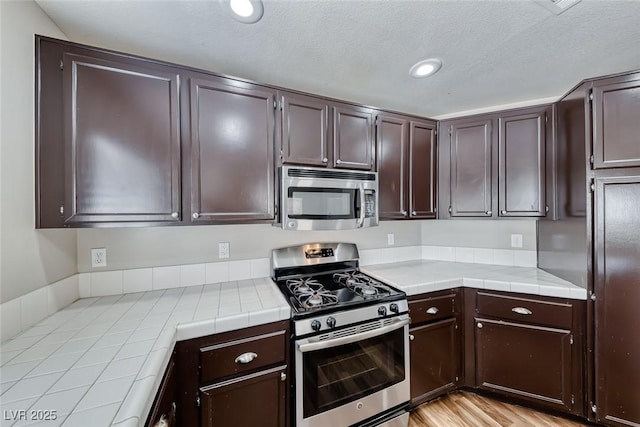2103 Falcon Crest Ave, North Las Vegas, NV 89031 - kitchen with appliances with stainless steel finishes, tile counters, dark brown cabinets, a textured ceiling, and recessed lighting