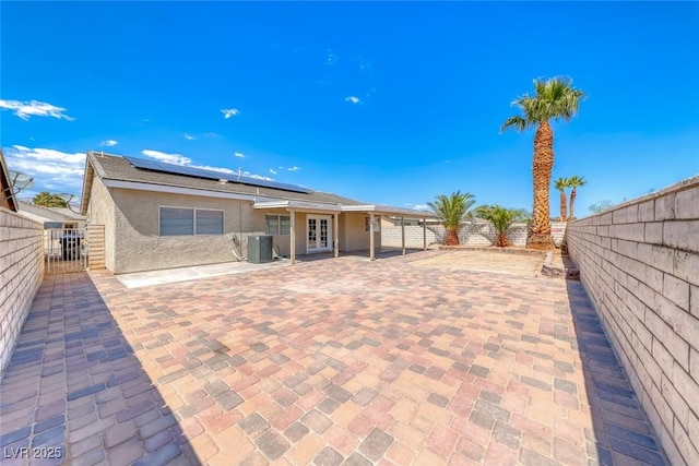 2103 Falcon Crest Ave, North Las Vegas, NV 89031 - back of property featuring french doors, a fenced backyard, stucco siding, a patio, and roof mounted solar panels