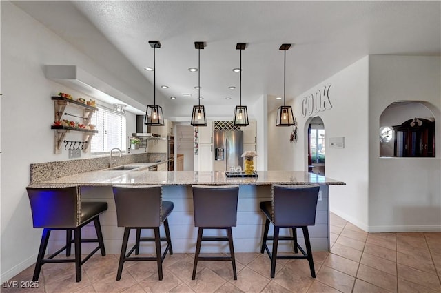 5725 N Durango Dr, Las Vegas, NV 89149 - kitchen featuring a sink, stainless steel fridge, wall chimney exhaust hood, a peninsula, and arched walkways