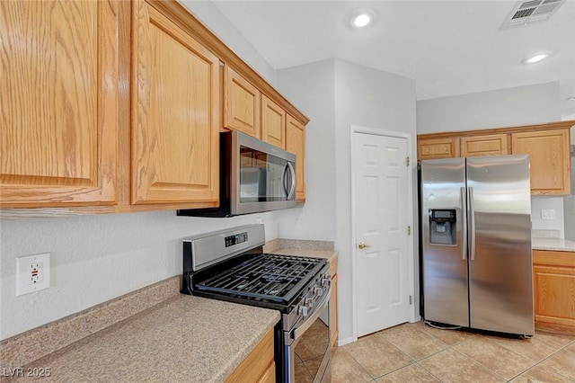 1574 Ward Frontier Ln, Henderson, NV 89002 - kitchen with appliances with stainless steel finishes, light countertops, light tile patterned flooring, light brown cabinetry, and recessed lighting