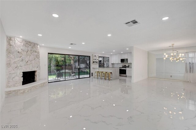 3013 Plaza De Rosa, Las Vegas, NV 89102 - unfurnished living room featuring recessed lighting, a chandelier, a stone fireplace, and light marble finish floors