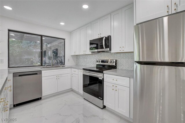 3013 Plaza De Rosa, Las Vegas, NV 89102 - kitchen featuring appliances with stainless steel finishes, a sink, light marble finish flooring, white cabinets, and tasteful backsplash