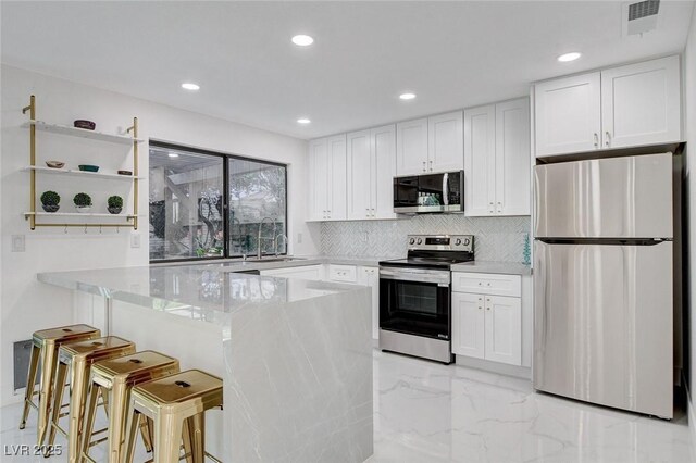 3013 Plaza De Rosa, Las Vegas, NV 89102 - kitchen featuring appliances with stainless steel finishes, open shelves, light marble finish flooring, a sink, and white cabinetry