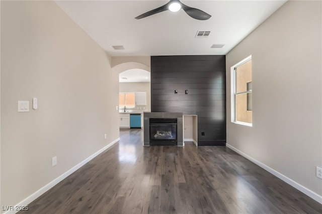 6260 Castle Kennedy St, Henderson, NV 89011 - unfurnished living room featuring arched walkways, ceiling fan, dark wood-style flooring, and a large fireplace
