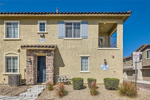 8490 Classique Ave Unit 101, Las Vegas, NV 89178 - view of front facade with stucco siding, cooling unit, stone siding, and a balcony