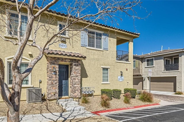 8490 Classique Ave Unit 101, Las Vegas, NV 89178 - view of front of home featuring stucco siding, a tile roof, cooling unit, an attached garage, and driveway