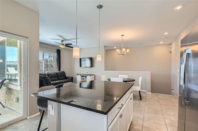 8490 Classique Ave Unit 101, Las Vegas, NV 89178 - kitchen with light tile patterned floors, white cabinets, stainless steel refrigerator, a center island, and dark stone countertops