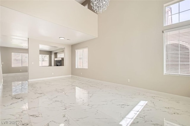 216 Sharp Edge Ave, North Las Vegas, NV 89031 - empty room with healthy amount of natural light, light marble finish floors, a chandelier, and baseboards