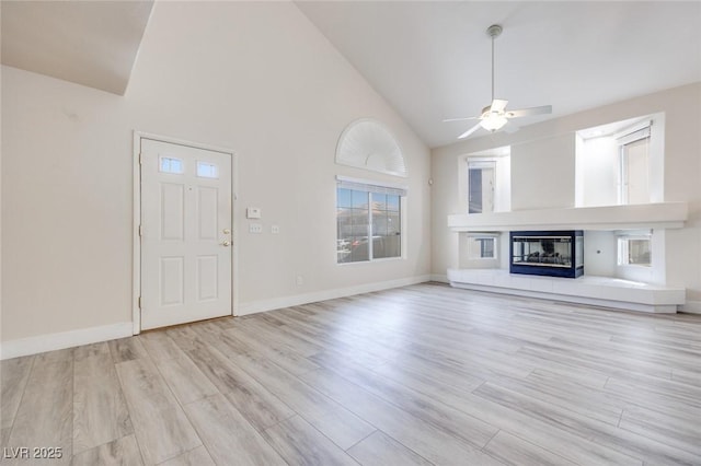1551 Echo Falls Ave, Las Vegas, NV 89183 - unfurnished living room featuring ceiling fan, wood finished floors, a tiled fireplace, high vaulted ceiling, and baseboards