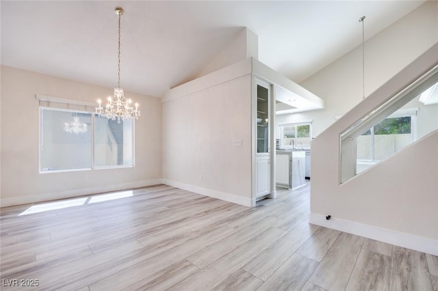 1551 Echo Falls Ave, Las Vegas, NV 89183 - unfurnished dining area featuring vaulted ceiling, a chandelier, light wood-type flooring, baseboards, and a sink