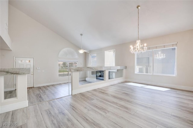 1551 Echo Falls Ave, Las Vegas, NV 89183 - unfurnished living room featuring light wood-style flooring, ceiling fan, baseboards, a chandelier, and high vaulted ceiling