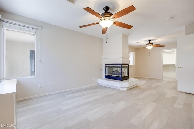 1551 Echo Falls Ave, Las Vegas, NV 89183 - unfurnished living room featuring a ceiling fan, a multi sided fireplace, light wood-style flooring, and baseboards