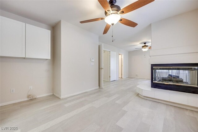 1551 Echo Falls Ave, Las Vegas, NV 89183 - unfurnished living room with a multi sided fireplace, ceiling fan, baseboards, and light wood-type flooring