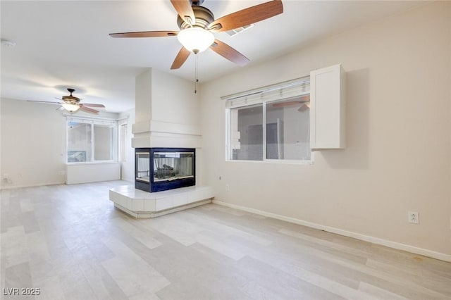 1551 Echo Falls Ave, Las Vegas, NV 89183 - unfurnished living room with a multi sided fireplace, a ceiling fan, baseboards, light wood-type flooring, and healthy amount of natural light