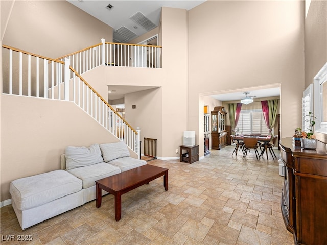 10612 Gum Tree Ct, Las Vegas, NV 89144 - living room with a high ceiling, stairway, light stone finish floors, a ceiling fan, and baseboards