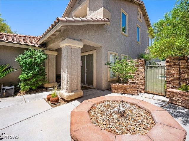 10612 Gum Tree Ct, Las Vegas, NV 89144 - view of exterior entry featuring stucco siding, a tiled roof, a gate, and a patio