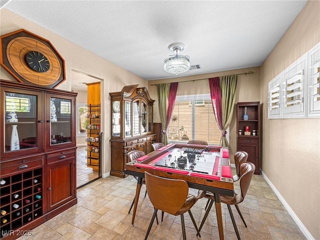 10612 Gum Tree Ct, Las Vegas, NV 89144 - game room with stone tile flooring, baseboards, a textured ceiling, a textured wall, and a chandelier
