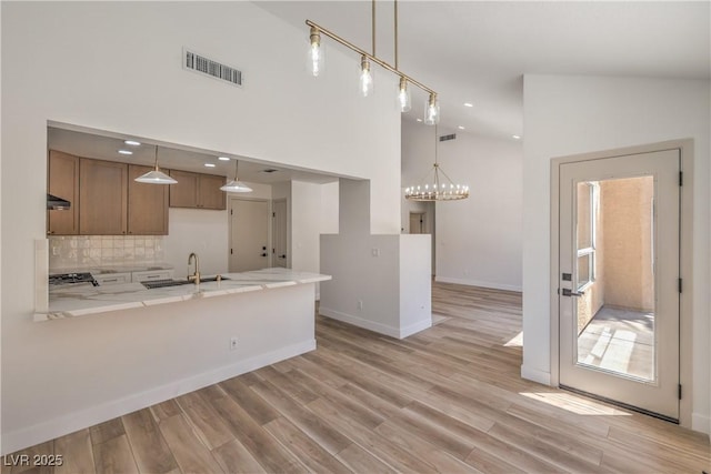 2117 Desert Peak Rd, Las Vegas, NV 89134 - kitchen with a peninsula, recessed lighting, brown cabinetry, light wood finished floors, and decorative backsplash