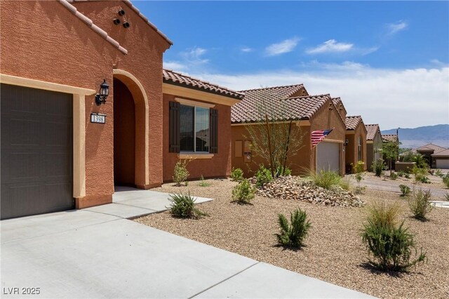 1398 Pin Cushion Rdg, Mesquite, NV 89034 - view of exterior entry with stucco siding, concrete driveway, an attached garage, a tile roof, and a mountain view