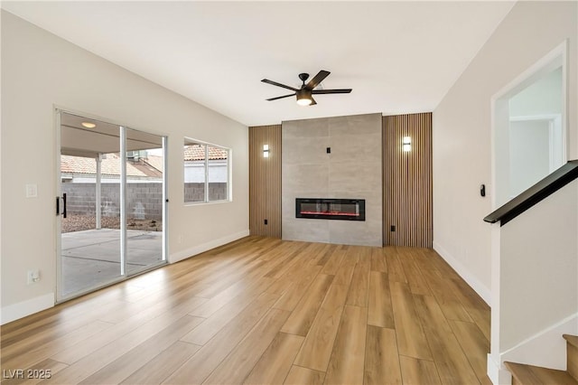 6388 Canyon Dawn Ave, Las Vegas, NV 89108 - unfurnished living room featuring ceiling fan, light wood-style floors, a fireplace, baseboards, and stairs