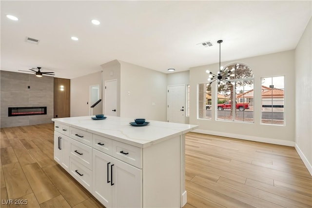6388 Canyon Dawn Ave, Las Vegas, NV 89108 - kitchen featuring open floor plan, light wood-style floors, ceiling fan, a center island, and a tile fireplace