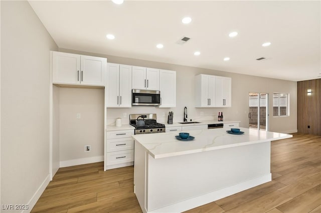 6388 Canyon Dawn Ave, Las Vegas, NV 89108 - kitchen with stainless steel appliances, a sink, light wood-style floors, a center island, and recessed lighting