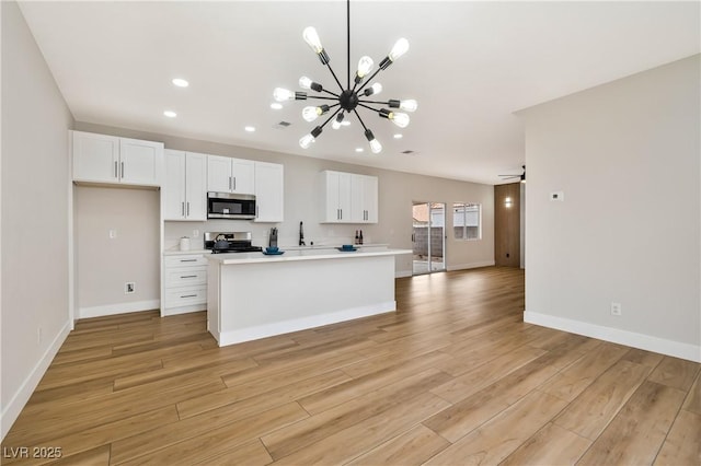 6388 Canyon Dawn Ave, Las Vegas, NV 89108 - kitchen with stainless steel microwave, stove, a chandelier, recessed lighting, and light wood-type flooring