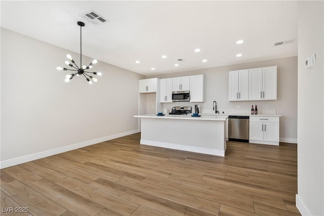 6388 Canyon Dawn Ave, Las Vegas, NV 89108 - kitchen with appliances with stainless steel finishes, a chandelier, white cabinetry, light wood finished floors, and recessed lighting