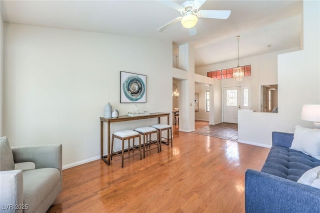 8428 Apple Hill Ct, Las Vegas, NV 89128 - living room with baseboards, light wood-style floors, ceiling fan, a chandelier, and vaulted ceiling
