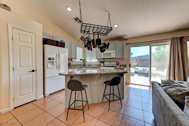 3823 Aspen Creek Ave, North Las Vegas, NV 89031 - kitchen featuring white appliances, a breakfast bar area, healthy amount of natural light, recessed lighting, and light tile patterned flooring
