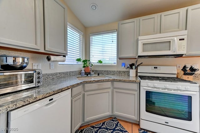 3823 Aspen Creek Ave, North Las Vegas, NV 89031 - kitchen with white appliances, a sink, light tile patterned flooring, light stone countertops, and lofted ceiling
