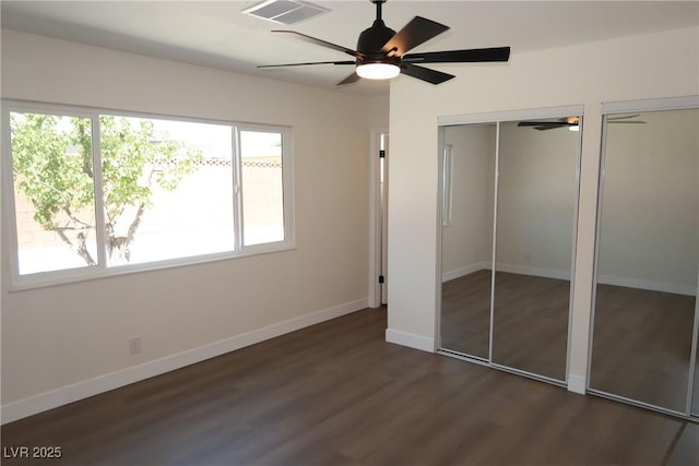 404 Vassar Ln, Las Vegas, NV 89107 - unfurnished bedroom featuring multiple windows, dark wood-style flooring, baseboards, and multiple closets