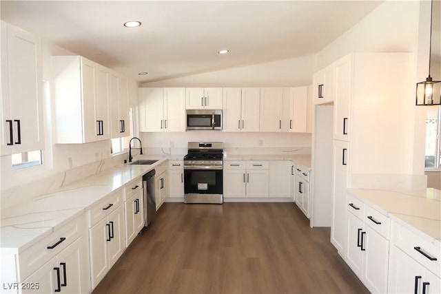 404 Vassar Ln, Las Vegas, NV 89107 - kitchen featuring appliances with stainless steel finishes, a sink, vaulted ceiling, light stone counters, and dark wood-style flooring