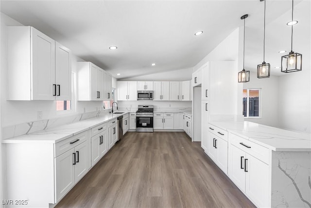 404 Vassar Ln, Las Vegas, NV 89107 - kitchen with appliances with stainless steel finishes, a sink, light stone countertops, a peninsula, and wood finished floors