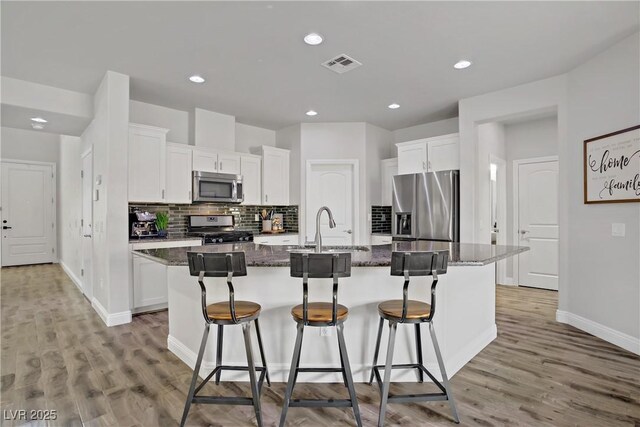 5742 Shadow Bend Dr, Las Vegas, NV 89135 - kitchen featuring stainless steel appliances, a sink, a center island with sink, a breakfast bar, and white cabinetry